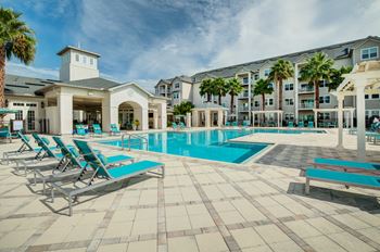 A swimming pool with chaise lounge chairs and a building in the background